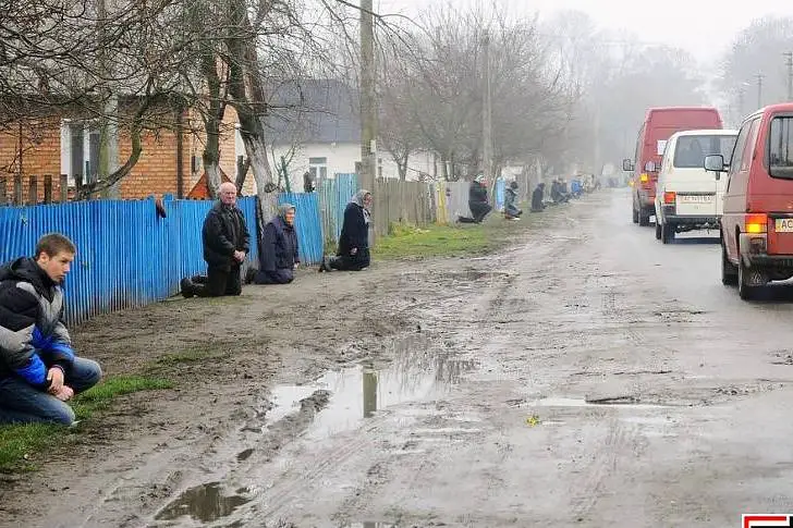 Жители украинского села на коленях перед похоронным кортежем